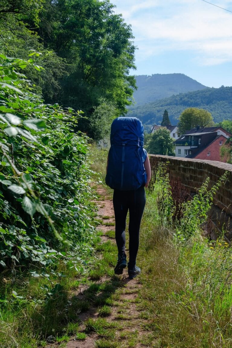 Wanderin mit großem Trekkingrucksack auf einem Wanderweg