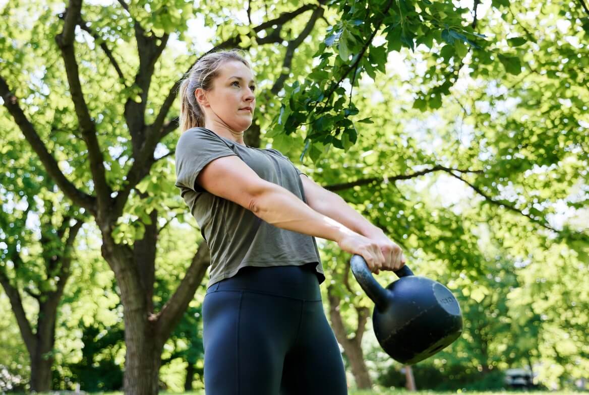 Frau trainiert mit HQ Germany Kettlebell im Freien – dynamische Übung